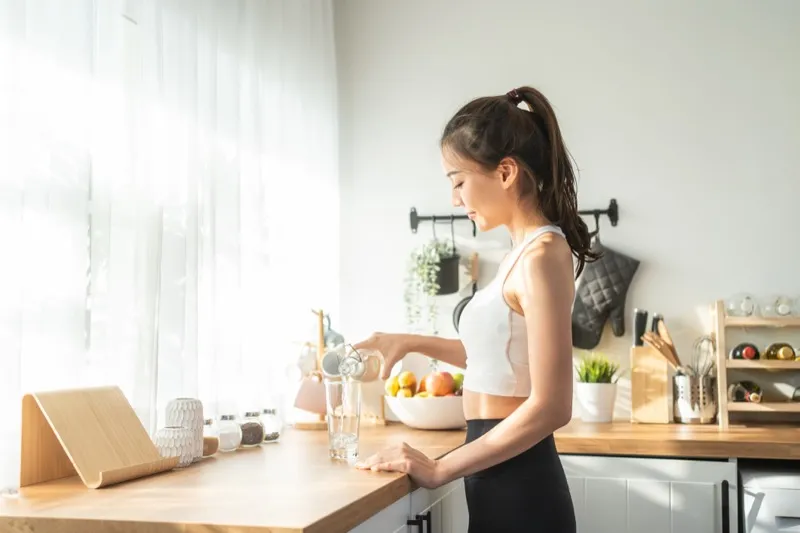 Woman using a countertop hydrogen water system in her kitchen